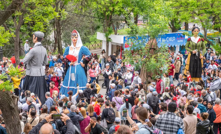 figuras de gigantes entre la multitud de la gente en medio de un parque, árboles
