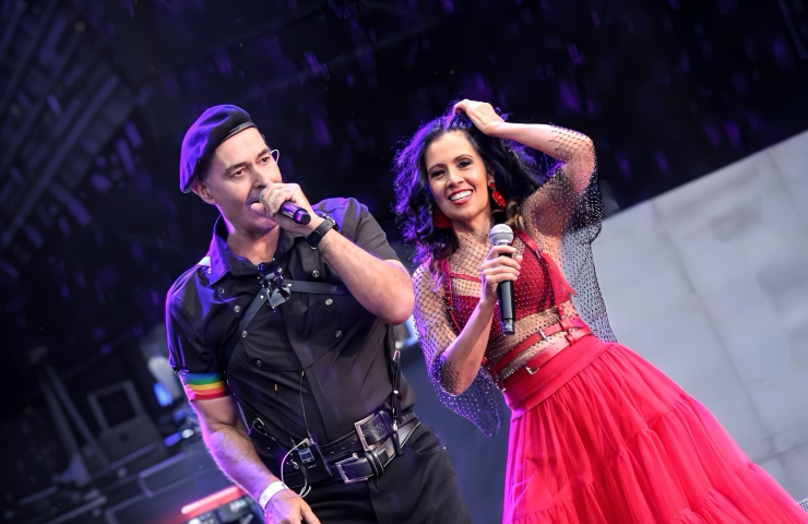 Un hombre con boina cantando acompañado de una mujer vestida de rojo.