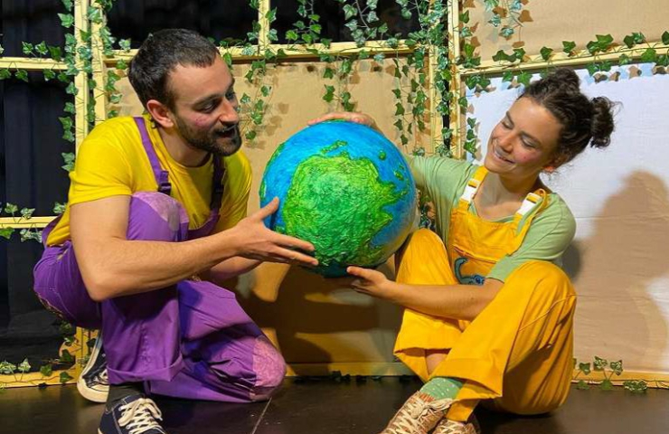 chico y chica sentados en el suelo mirando el globo terráqueo que sostienen entre las manos