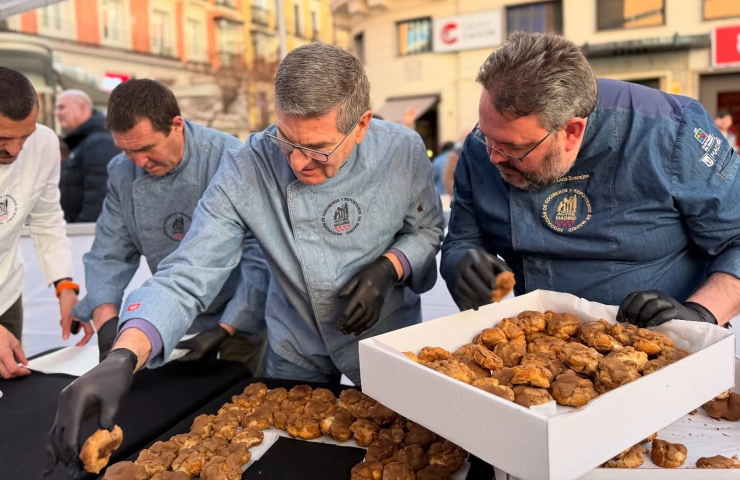 Cocineros vestidos con chaquetillas, guantes negros colocan diferentes tipos de rosquillas