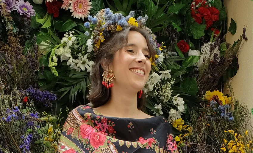 mujer sonrientes con mantón de flores negras y diadema de flores en el pelo