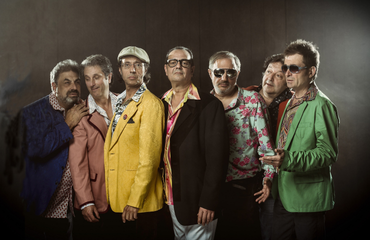 Siete hombres vistiendo americanas de colores sobre fondo negro