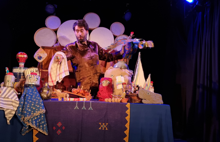hombre en escenario con una mesa con títeres