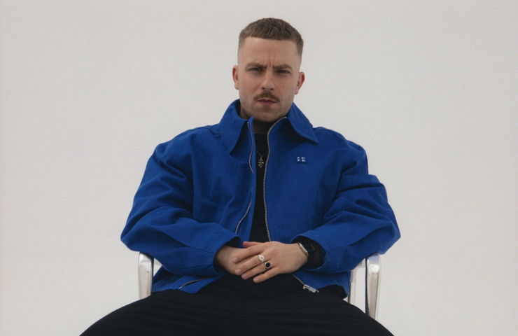 Hombre con chaqueta azul sentado en silla mirando a cámara